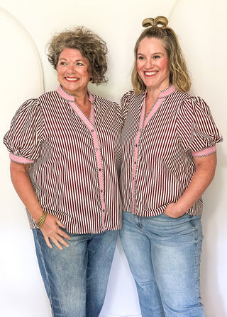 Two women wearing burgundy stripe button up top 