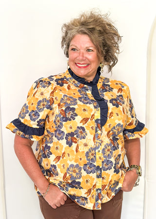 Bold Navy and golden blooms on this short sleeve top with navy ruffle detail on the sleeves, collar and 1/2 way down the front. Buttons up the front.