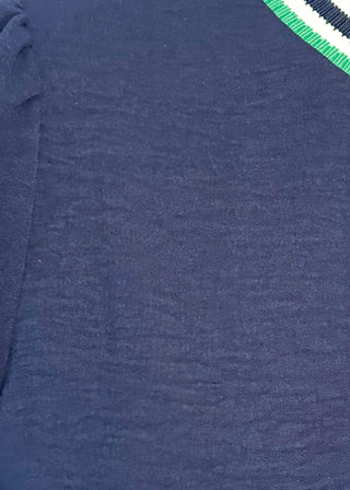Close up of navy long-sleeve top with green-and-white striped trim at neckline, cuffs, and hem.