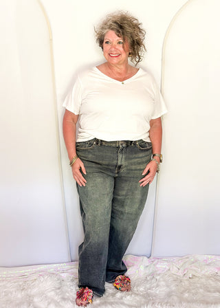 Woman wearing a white shirt and blue jeans standing against a white background