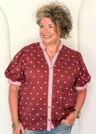 woman wearing burgundy button up top with polka dots.
