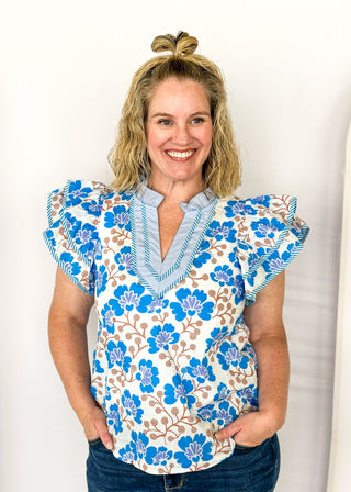 blue floral with large double ruffle short sleeve top - ruffles trimmed in blue and white striped contrast also runs along v neck- ruffle color - brown stems