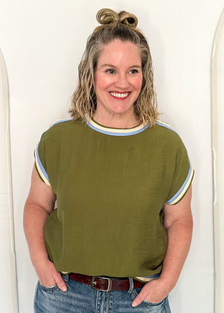 women wearing olive green top with cap sleeves and crew neckline, styled with jeans.