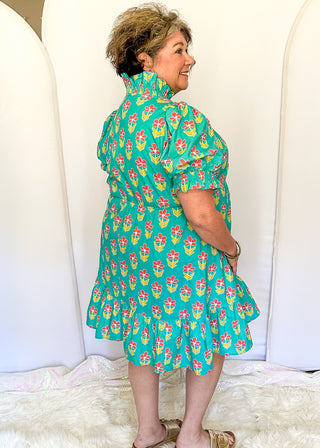 Mint green floral dress with colorful pink flowers, featuring short puff sleeves, ruffled neckline, smocked waist, and flowy skirt.