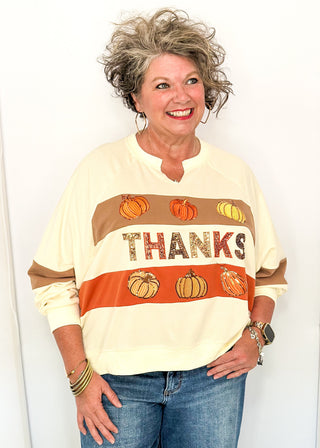 woman modeling a cream long sleeve top with pumpkins and THANKS in sequins