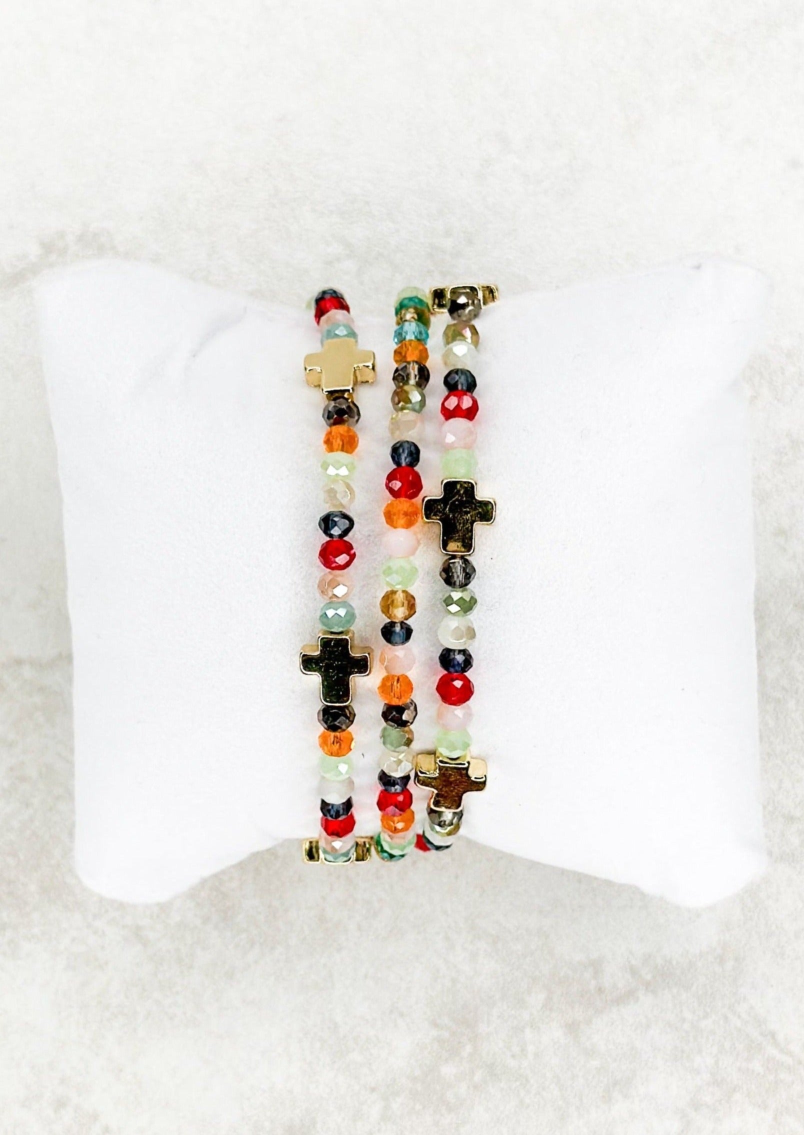 Three strand multi-color beaded stretch bracelet set with gold cross beads throughout.