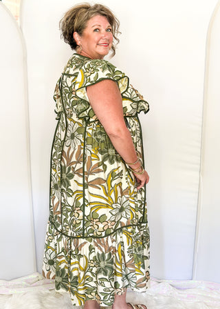 Ruffle cap sleeve maxi dress. off white background with green botanical print.  Dark green piping detail around v-neck, sleeves, bottom tier.  dark green ties on each side of waist. 