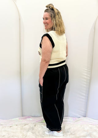 Black balloon style pants with rope drawstring waist. White stitching around pockets and crop cut.