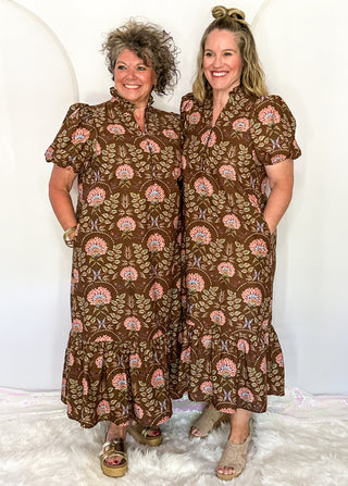 two women wearing brown midi dress with floral pattern standing side by side.
