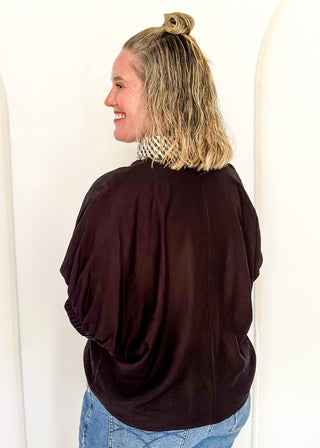 Women's black top featuring a gingham contrast neckline, loose silhouette, and subtle puff sleeves