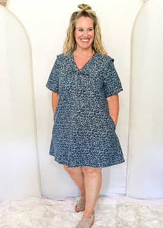 Denim and leopard print jacquard dress with short sleeves and pockets.  Sailor Collar with tie at the v-neck.  Buttons up the front of the dress and hits above the knee. 