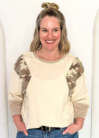 Cream knit colorblock top with camo print shoulder panels, ribbed taupe sleeves and cuffs, and a crew neckline.
