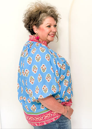 Bright blue 3/4 sleeve top with floral pattern, smocked collar with matching coral floral neckline and hem. 