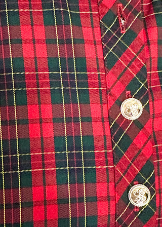 Close-up of a red and green plaid shirt fabric with gold buttons on the placket.
