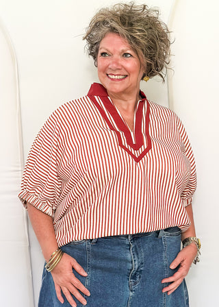 Woman wearing a brick and cream striped dolman-sleeve top with contrast trim, styled for a casual and relaxed fit.
