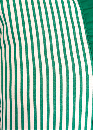 Close up of green vertical striped collared dress with button-down front with green contrast, 3/4 sleeves, midi length, and side pockets.