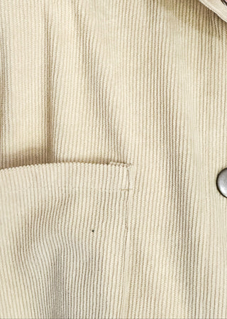 Close up of colorblock corduroy shacket with front and side pockets. featuring cream, camel, forest green, and dark red panels, long sleeves, and snap-front closure