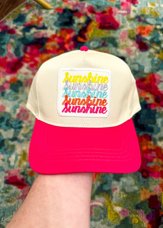 Cream snap back ball cap with a hot pin bill and embroidered patch “Sunshine, Sunshine, Sunshine, Sunshine, Sunshine” in bright multi color tones.