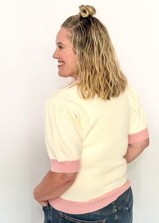 Cream short sleeve sweater with puff sleeves, pink trim, and sequin peppermint candy accents on the front