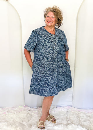 Denim and leopard print jacquard dress with short sleeves and pockets.  Sailor Collar with tie at the v-neck.  Buttons up the front of the dress and hits above the knee. 