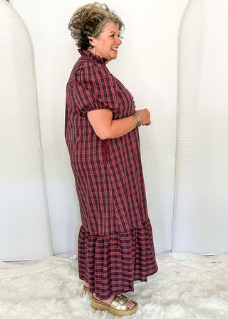 side view of woman wearing a plaid midi dress with puff sleeves and a tiered ruffle hem