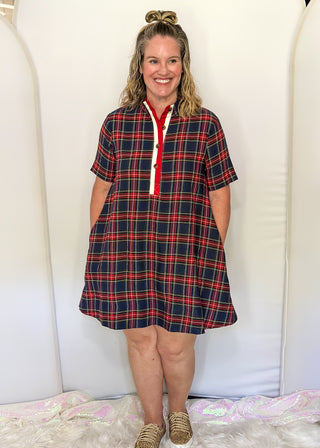 Woman wearing a plaid dress standing against a white background