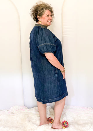 Women's dark blue denim dress featuring statement puff sleeves and contrast stitched detailing around the neckline.
