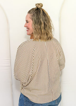 Woman wearing a brown and cream striped dolman-sleeve top with contrast trim, styled for a casual and relaxed fit.