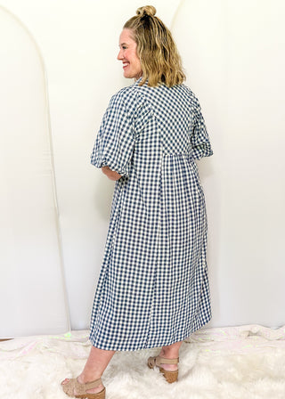 Woman wearing long blue gingham dress with short sleeves