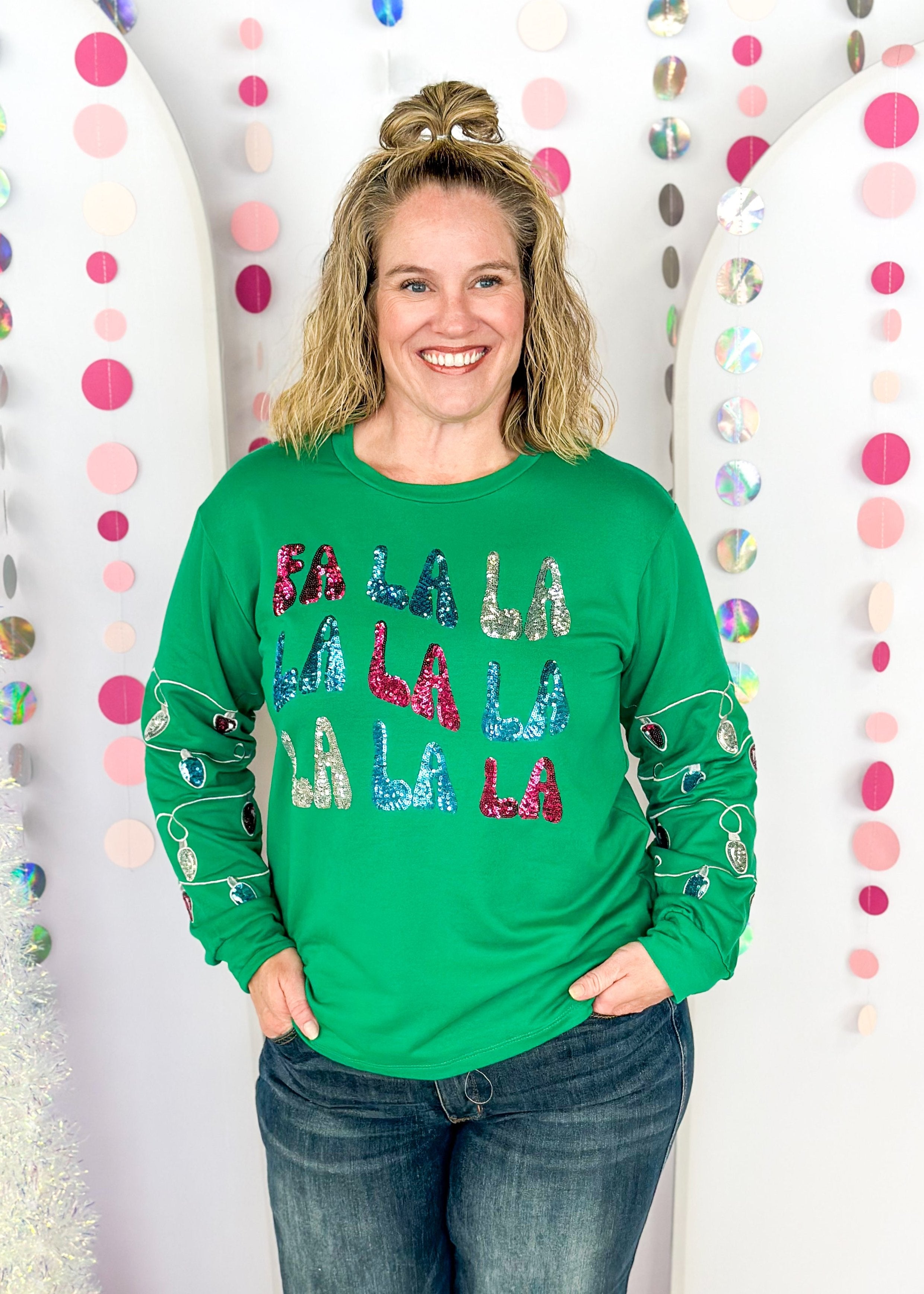 green long sleeve top with fa la la la la la across the front in sequin patches with sequin Christmas lights on the sleeves starting around the elbow down