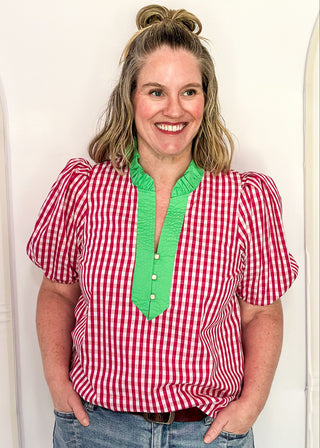 Women’s gingham blouse with decorative buttons and statement neckline detail.