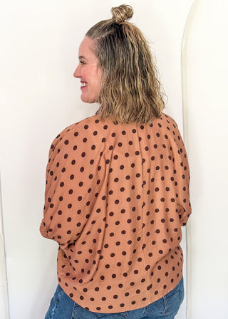 woman in camel dolman top with chocolate polka dots.