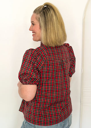 side view of woman wearing a plaid puff sleeve top in red with short sleeves and a V-neckline.
