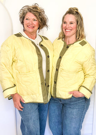 Light sage green quilted jacket with darker contrast trim, long sleeves, patch pockets, and button-front closure