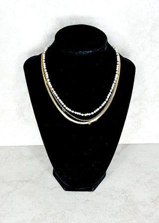 Trippled strand Necklace on a black velvet stand against a white background