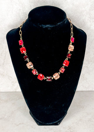 Pink and red gemstone necklace displayed on a black neck form 