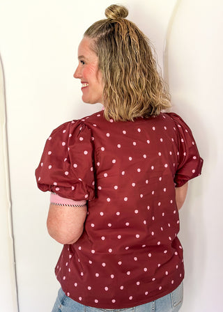 woman wearing burgundy button up top with polka dots.