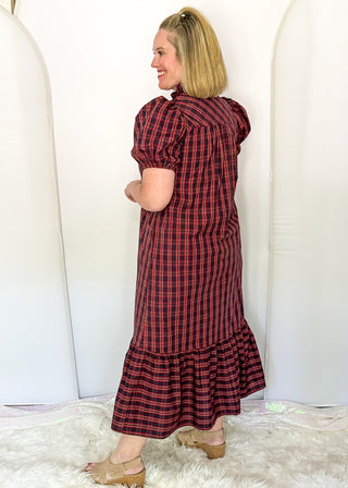 side view of woman wearing a plaid midi dress with puff sleeves and a tiered ruffle hem