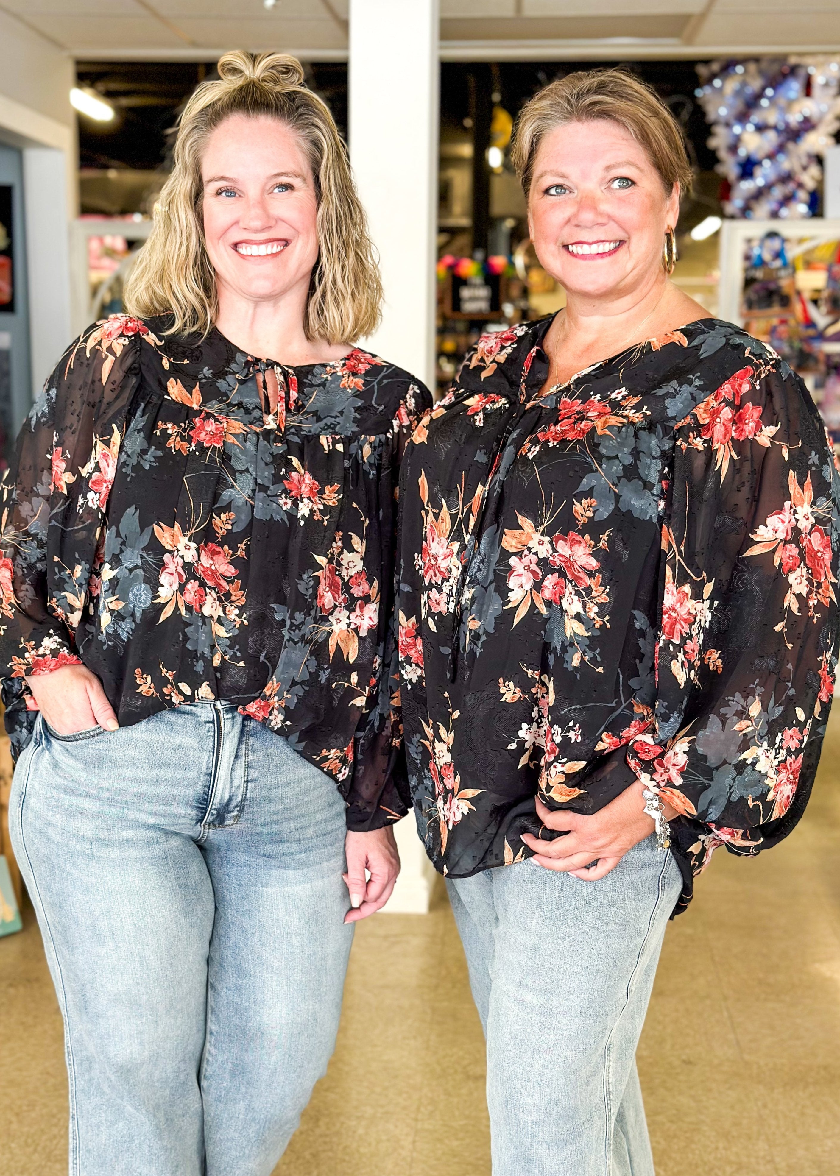 black floral top with sheer long sleeves - flowers are rust, orange and bluish gray, tie neck lined