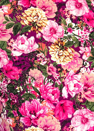 A close-up of a vibrant floral fabric print featuring large pink, magenta, and peach flowers with green leaves on a dark purple background.