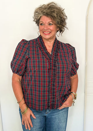 woman wearing a plaid puff sleeve top in dark navy with short sleeves and a V-neckline.
