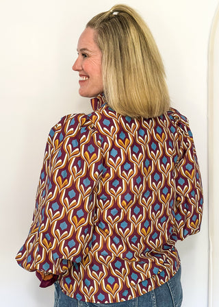Wine-colored geometric print blouse with long puff sleeves and smocked cuffs.