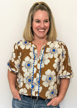 Mocha colored floral blouse featuring white and blue blooms with blue scalloped trim. 