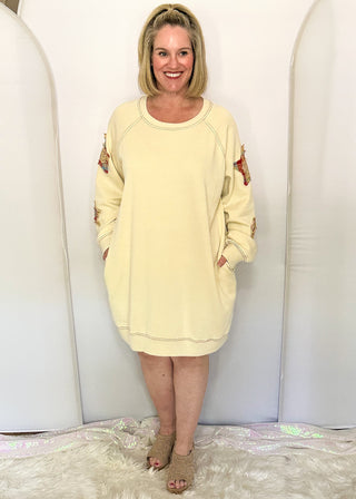 woman modeling a cream sweatshirt dress with fabric star patches