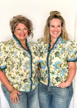 light blue and dark green botanicals on an ecru background.  Short ruffle sleeves, v-neck ruffle collar.  