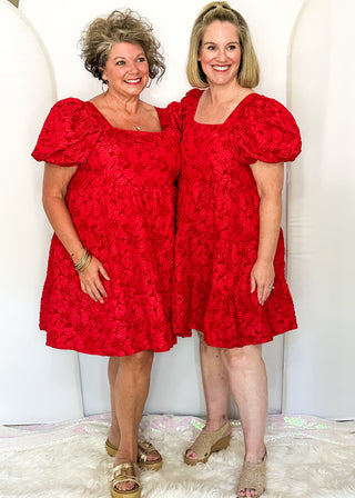 Two women wearing red jacquard babydoll dresses with square necklines and short sleeves.