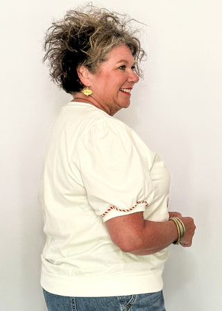 side view of woman modeling a short sleeve puff sleeve top with fabric gingerbread man with sequins and embroidery details