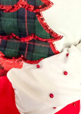 White long sleeve Christmas top with red neckline and cuffs, featuring a plaid Christmas tree appliqué with red sequin trim on the front. Red pearl accent the sleeves for a festive touch.”