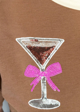 close up of sparkling sequin cocktail glasses with pink bows and cream neckline.