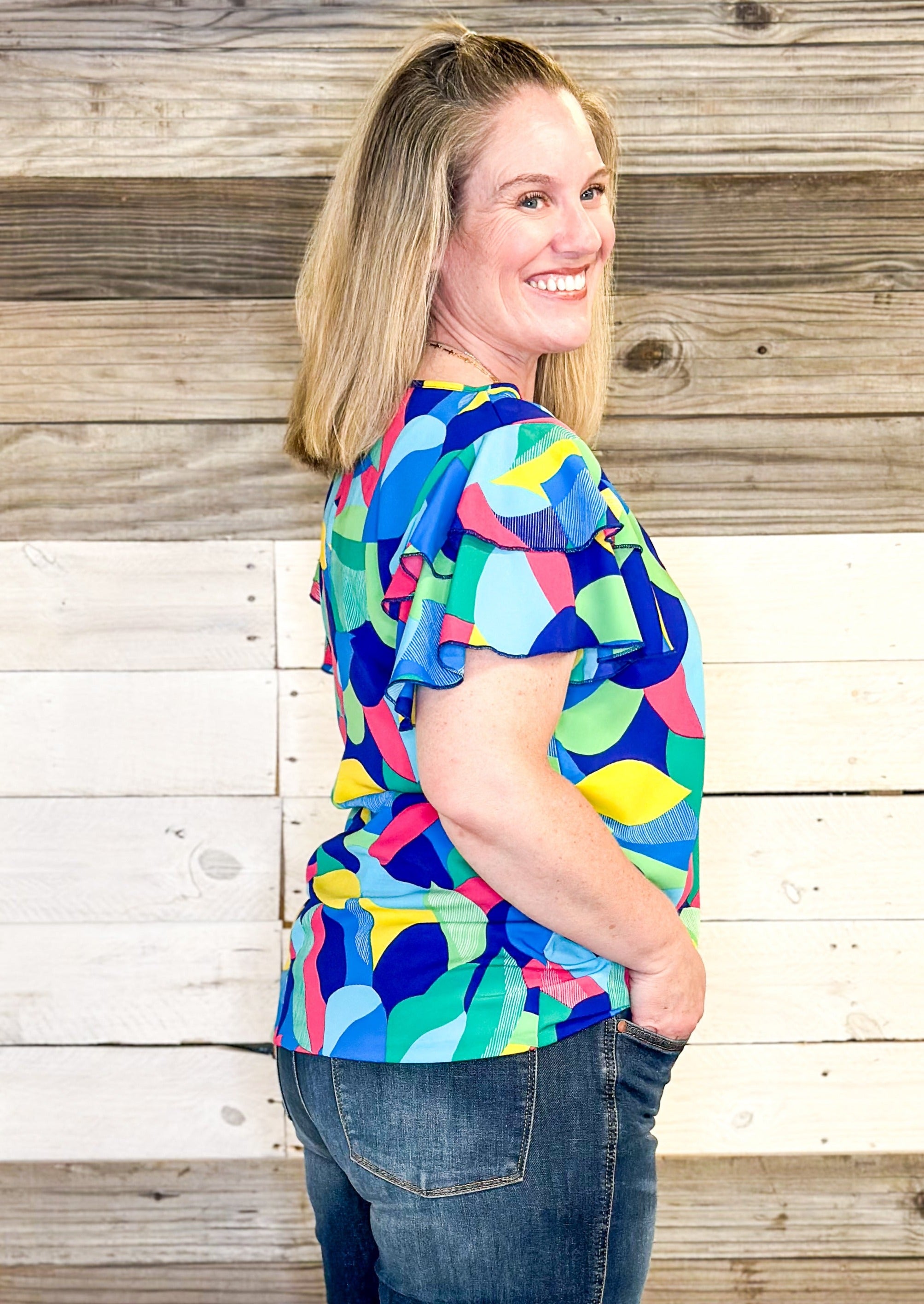 bright colors form a geometric pattern - no stretch recommended to size up - double ruffle sleeve - short sleeve top - colors of blues, pink, green, yellow